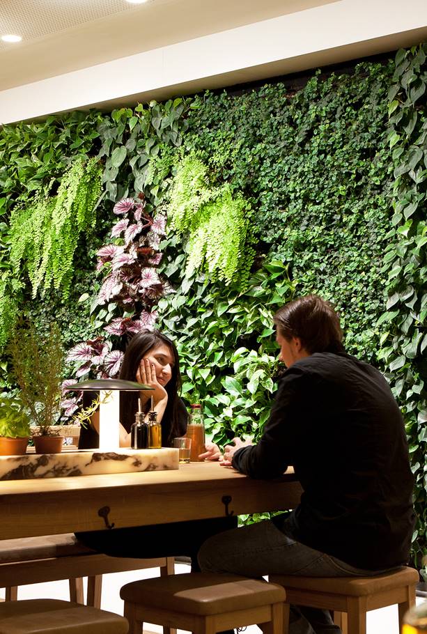 Plantenwand achter mensen die uiteten zijn in vapiano restaurant