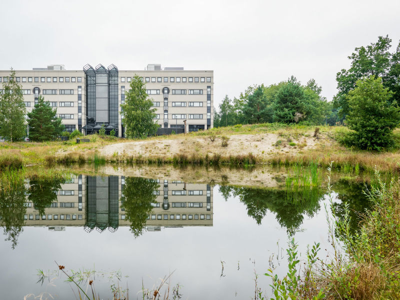 Zicht op de Achmea Campus vanaf de kant van een meertje